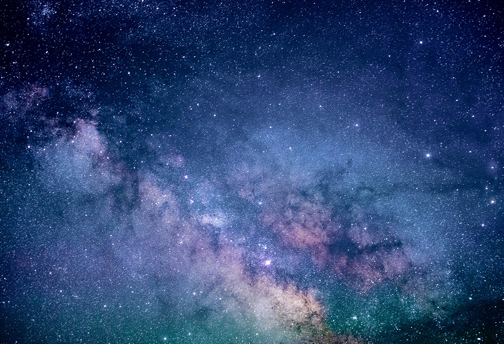 A stunning view of the galaxy with countless stars, deep blue and purple hues, and a glowing nebula in the background.